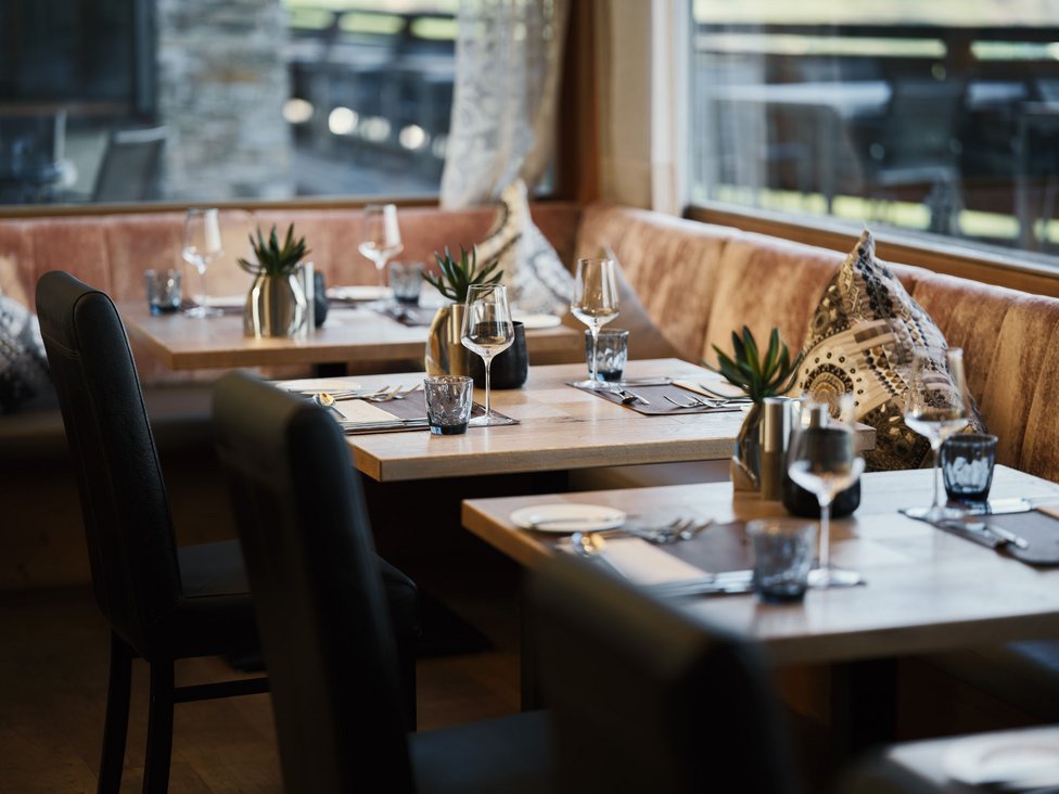 Eleganter eingedeckter Restaurantbereich mit Holztischen und Ledersesseln