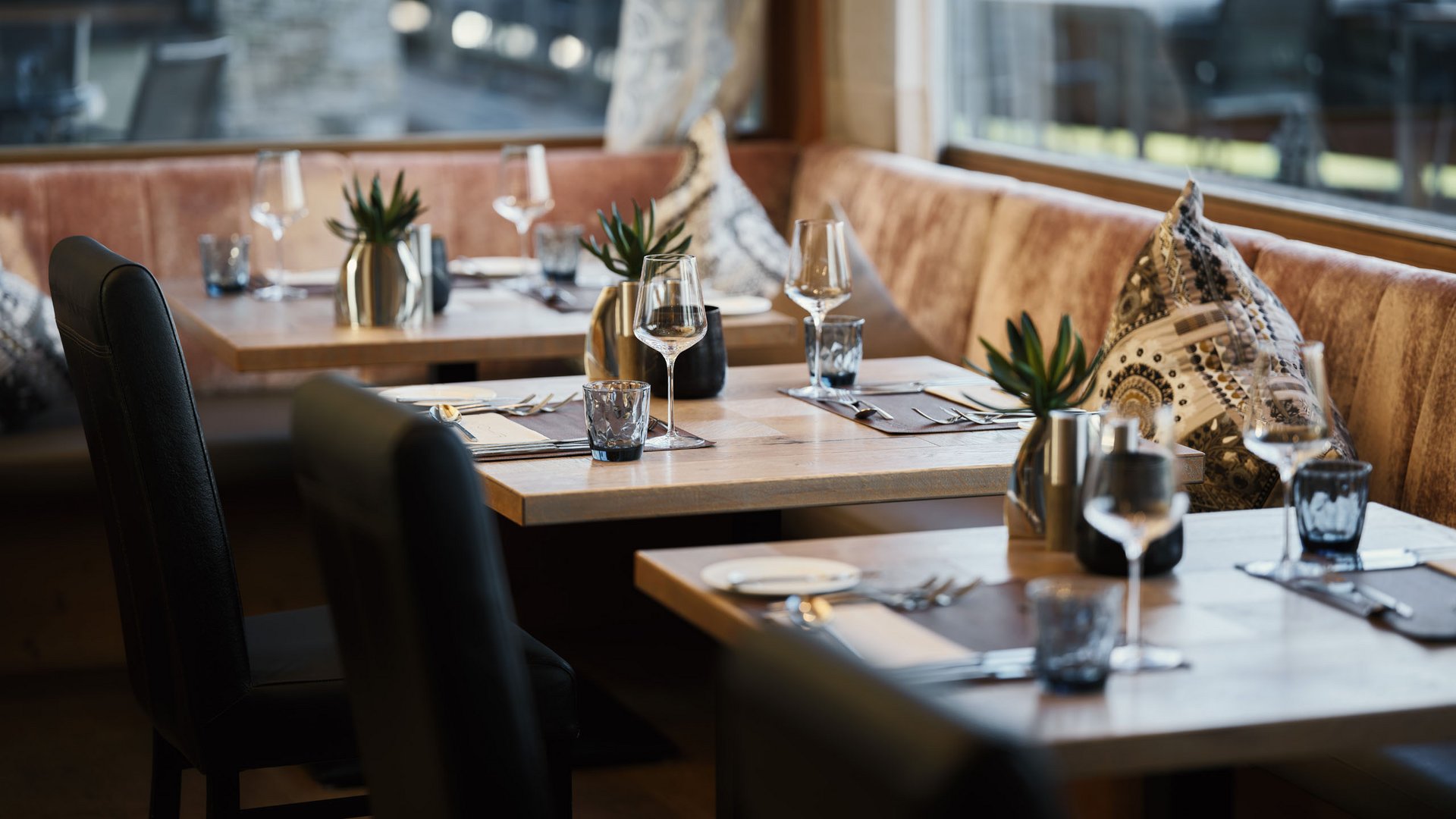 Eleganter eingedeckter Restaurantbereich mit Holztischen und Ledersesseln