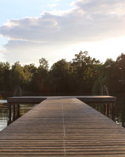 Watery fun galore around your wellness hotel in Tyrol Wooden pier over calm lake with trees in background at sunset