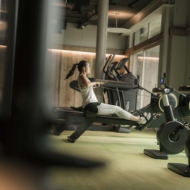 Frau trainiert auf dem Rudergerät im modernen Fitnessstudio