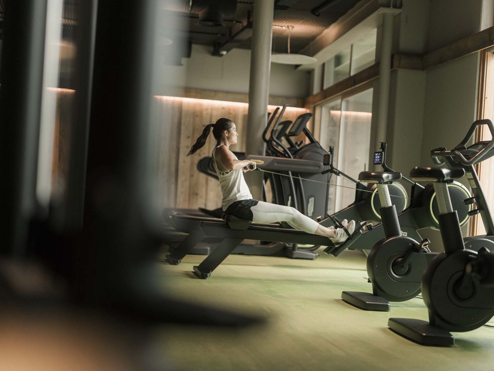 Frau trainiert auf dem Rudergerät im modernen Fitnessstudio
