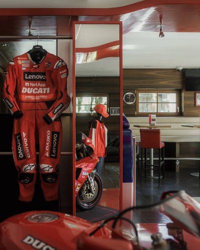 Rotes Ducati-Rennanzug und Motorrad in einem Café mit Sitzbereich