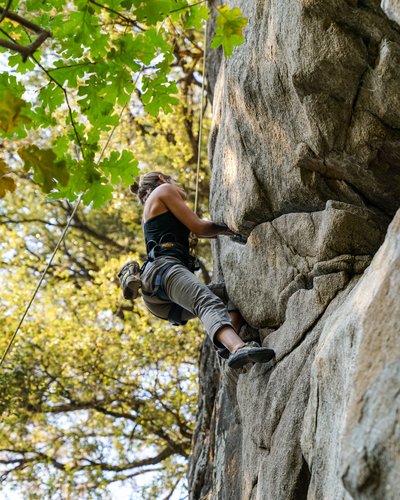 Frau klettert an felsigem Fels mit Gurten und Seil
