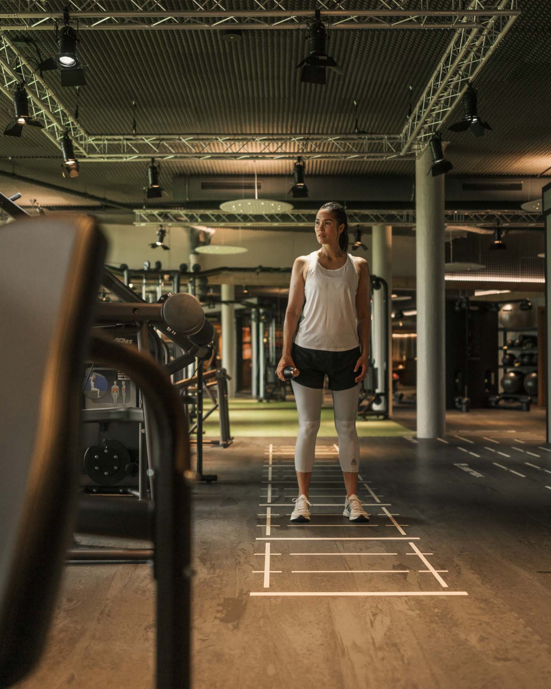 Wellness und Luxus: Ihr Hotel in Tirol Frau im Fitnessstudio hält Hantel und steht auf markiertem Boden