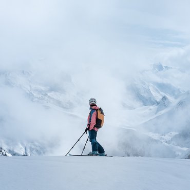 Skifahrer in Berglandschaft umgeben von Nebel und Schnee