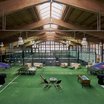 Indoor-Padel-Tennisplätze mit Spielern und Sitzbereich auf grünem Teppich