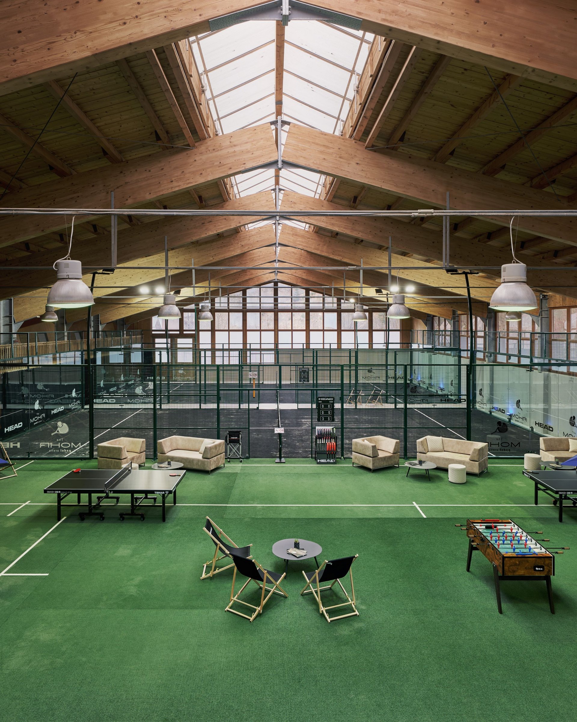 Indoor-Padel-Tennisplätze mit Spielern und Sitzbereich auf grünem Teppich