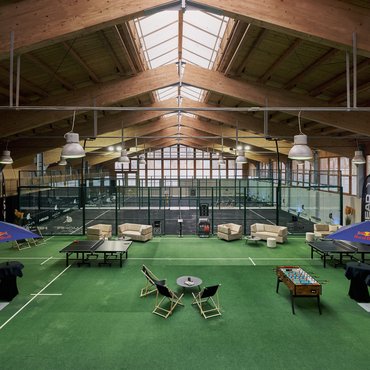 Indoor-Padel-Tennisplätze mit Spielern und Sitzbereich auf grünem Teppich
