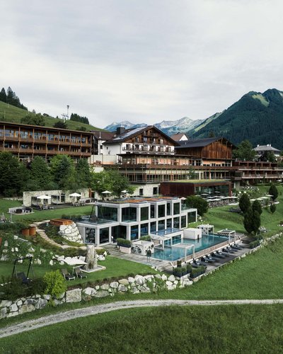 Hotelanlage mit Außenpool und Liegen in den Bergen bei bewölktem Himmel