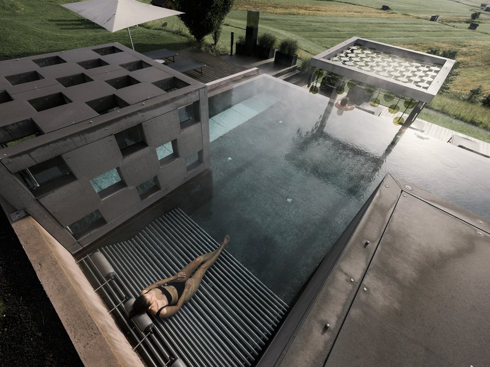 Frau entspannt in modernem Pool mit Sitzplatz und ländlicher Aussicht